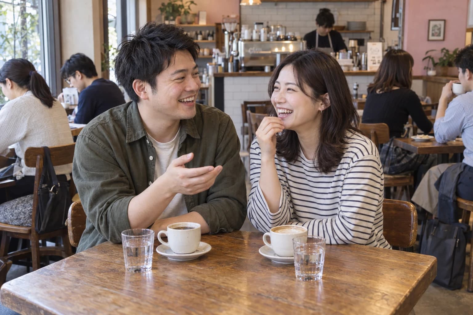 カフェで笑顔で会話を楽しむ男女のイメージ