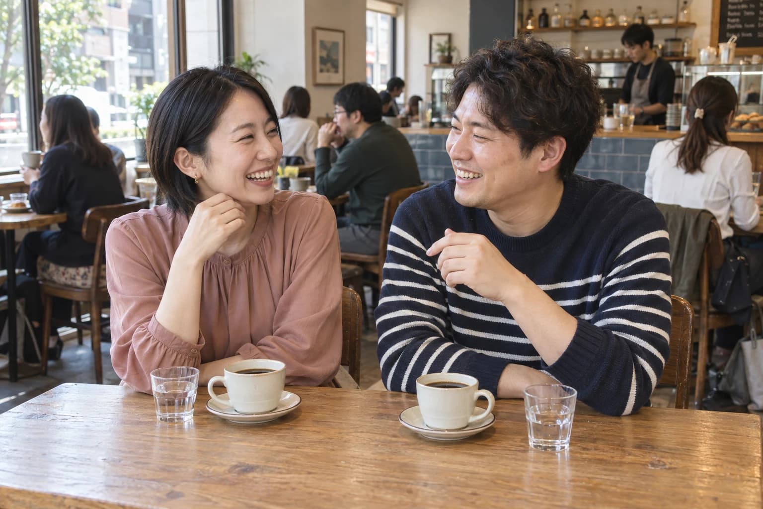 カフェで笑顔で会話を楽しむ男女のイメージ